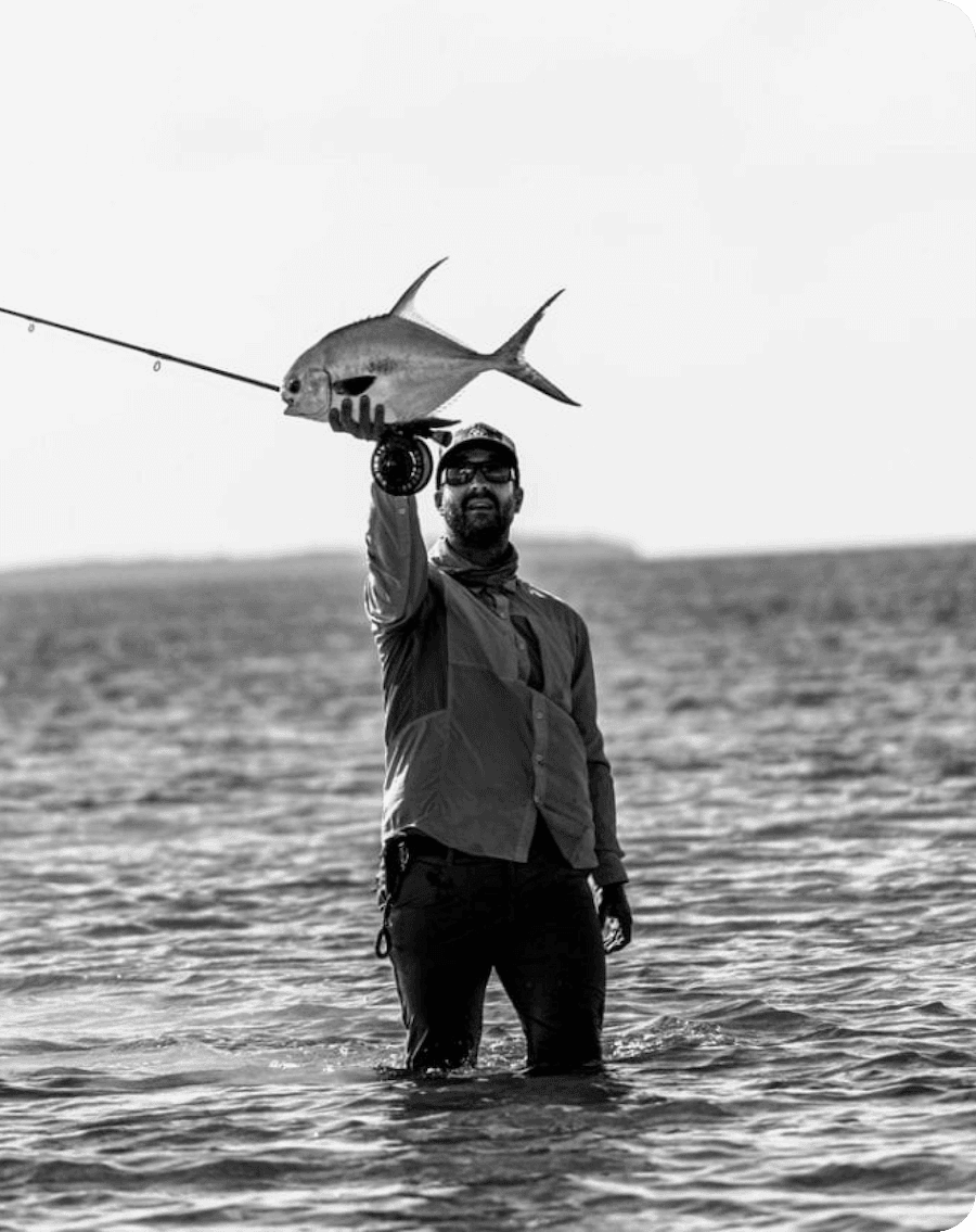 An angler, wading in the sea, holding up a fish